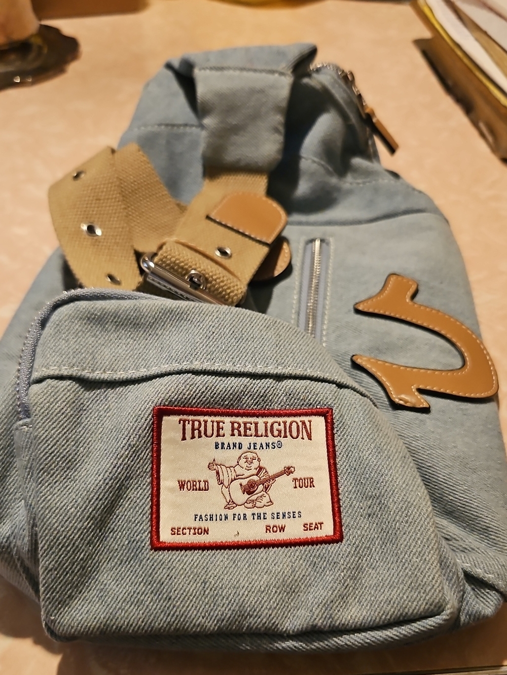 True Religion Light Blue Denim Sling Bag with Tan Accents and Red Logo Patch